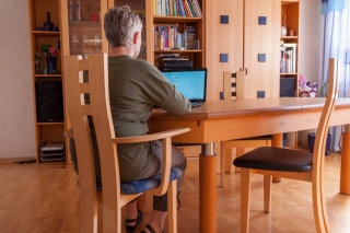 Eine Frau, die auf einem Massivholzstuhl aus der Xen- Serie sitzt und an einem Laptop arbeitet.
