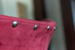 Nahaufnahme von Polster-Nägeln in einem roten Echt-Lederbezug einer Rückenlehne.