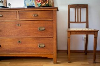 Ein alter, restaurierter Stuhl neben einem altem Schrank.