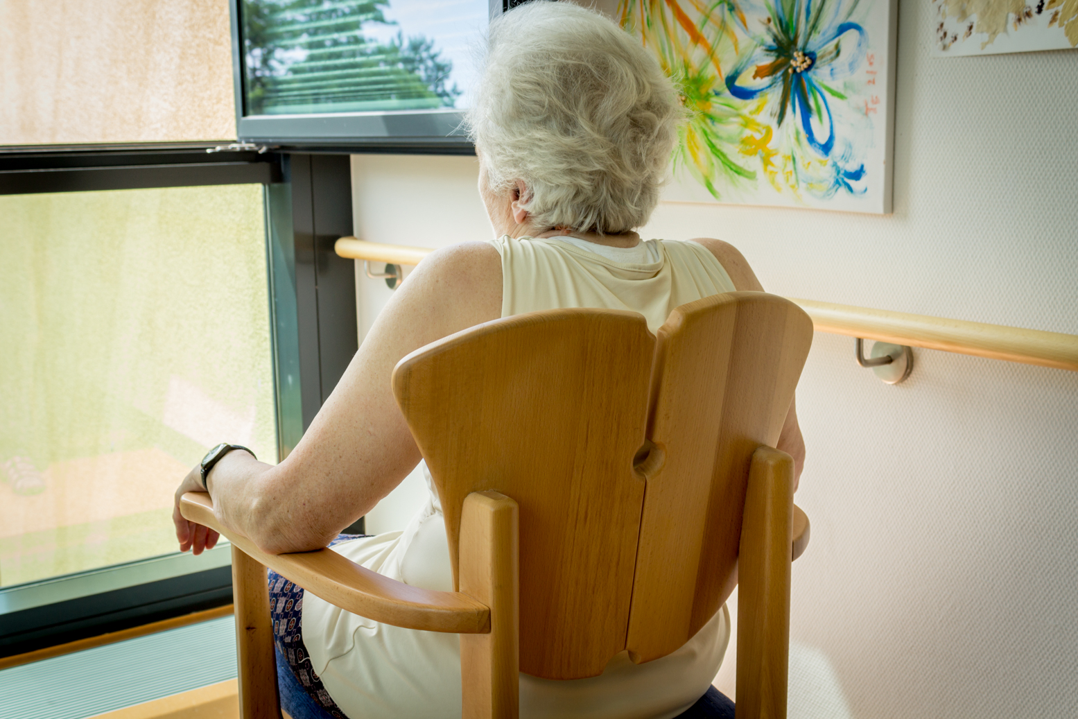 Frau im Seniorenheim sitzt im Massivholz-Stuhl.